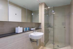 y baño con lavabo y ducha. en Meriton Suites Campbell Street, Sydney en Sídney