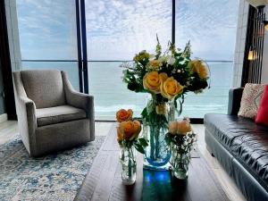 a living room with a vase of flowers on a table at Ocean View Luxury Condo Oceanfront and Pool in San Diego