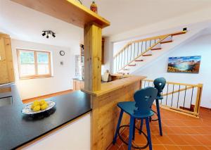 a kitchen with a counter and two blue stools at Ferienhaus im modernen Landhauscharme mit Bergblick und Garten in Bischofswiesen