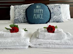 two towels with roses on a bed with a happy price pillow at Ocean View Luxury Condo Oceanfront and Pool in San Diego