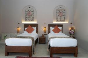 two beds in a room with two windows at Nozol Al Rayaheen By Sharjah Collection in Khor Fakkan