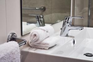 bagno con lavandino, asciugamani e specchio di Rochavau Hotel a Portimão