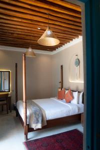 1 dormitorio con 1 cama con sábanas blancas y almohadas de color naranja en Nozol Al Rayaheen By Sharjah Collection, en Khor Fakkan