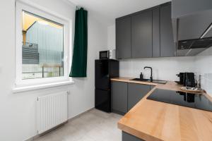 uma cozinha com armários a preto e branco e uma janela em Apartments with Garden Dmowskiego 81 by Renters em Poznań