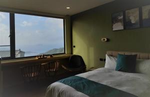 a bedroom with a bed and a large window at 95 Pavilion in Jiufen