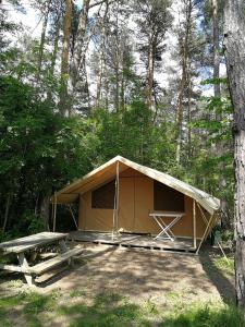 a tent with a picnic table in a forest at Camping l'Hirondelle Drôme in Menglon