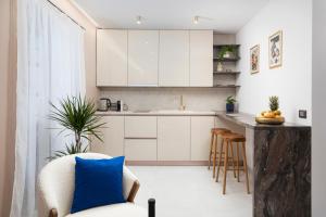 uma cozinha com armários brancos e uma almofada azul numa cadeira em Twins Amphitheatre Apartments em Pula