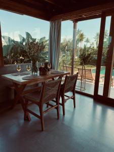 uma sala de jantar com mesa, cadeiras e janelas em Bruann residence villa 1, Seseh, Perenenan, amazing sunset view and privacy, 2 bedroom em Munggu