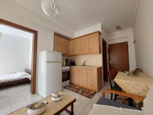 a kitchen with a table and a white refrigerator at KLEOPATRA APARTMENT in Neoi Epivates