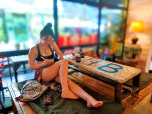 a woman sitting on a bench at a table at Back Home Backpackers in Bangkok