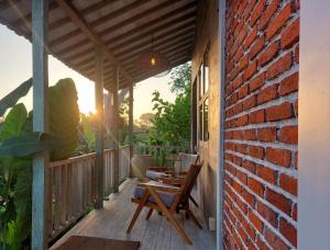 a wooden porch with a table and chairs on a brick wall at Spaces Bali Unique Boutique Hotel in Munggu