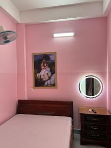 - une chambre rose avec un lit et un miroir dans l'établissement Nhà nghỉ 2552, đường D4 , KDC Võ Thị Sáu , phường Thống Nhất , thành phố Biên Hòa, à Biên Hòa