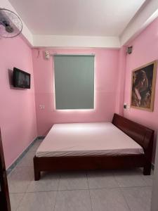 - une chambre avec un lit dans un mur rose dans l'établissement Nhà nghỉ 2552, đường D4 , KDC Võ Thị Sáu , phường Thống Nhất , thành phố Biên Hòa, à Biên Hòa