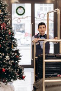 un hombre sentado en una silla junto a un árbol de Navidad en The Diamond Hotel Baku en Baku