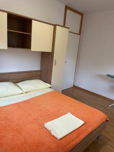 - une chambre avec un lit et une couverture orange dans l'établissement Apartman Lucija Biograd, à Biograd na Moru