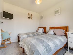 a bedroom with two beds and a tv on the wall at Diglis Lock Cottage in Worcester