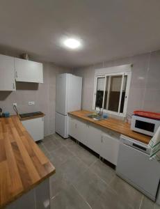 uma cozinha com electrodomésticos brancos e uma bancada de madeira em Casa Tena em Partida de La Cañada