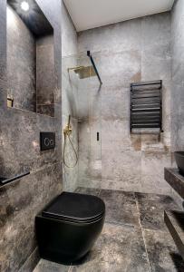 y baño con aseo negro y ducha. en Apartamenty Laguna Beskidów - A54, en Zarzecze