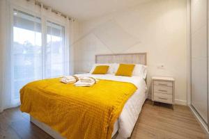 a bedroom with a bed with a yellow blanket on it at La Terraza De Loyola in Oviedo