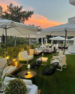 un patio avec des chaises, des tables et des parasols dans l'établissement Hotel San Francisco, à Lignano Sabbiadoro