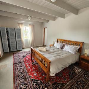 a bedroom with a large bed and a rug at Karoo Leeu Cottage in Oudtshoorn