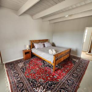 a bedroom with a bed on a rug with a table at Karoo Leeu Cottage in Oudtshoorn