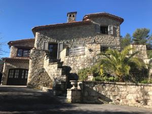 una casa de piedra con una palmera delante de ella en Bas de villa- Bastide zebra, en Contes