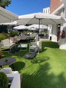 un patio avec des chaises, des tables et des parasols dans l'établissement Hotel San Francisco, à Lignano Sabbiadoro