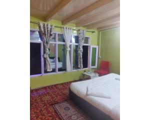 Sohail Home Stay, Pahalgam في باهالجام: غرفة نوم بسرير ونافذة بها كرسي احمر