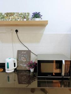 a kitchen counter with a microwave and flowers on it at Tenang Retreat Holiday Home in Kajang