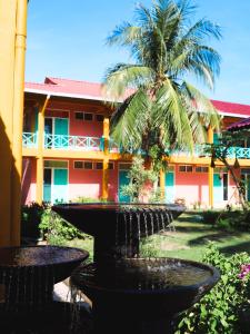 a fountain in front of a building with a palm tree at papaya resort in Kampung Tekek