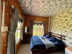 a bedroom with a bed in a brick wall at Hoa Son Village Da Lat in Xuan An