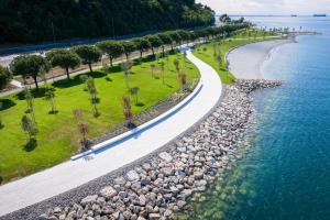 a road next to a beach with trees and the water at Tri Gracije in Koper