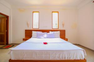 a bedroom with a white bed with a red flower on it at Olga's Place Hikkaduwa in Hikkaduwa