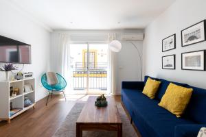 een woonkamer met een blauwe bank en een tafel bij Azahar in Sevilla