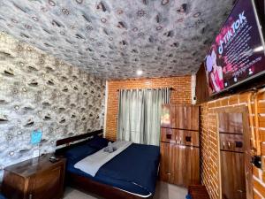 a bedroom with a bed and a tv and a brick wall at Hoa Son Village Da Lat in Xuan An