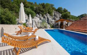 una piscina con sillas y sombrillas junto a una piscina en Stunning Home In Vrgorac With Kitchen, en Vrgorac