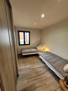 2 łóżka w pokoju z drewnianą podłogą w obiekcie Appartement en Chalet 4 étoiles w mieście LʼHuez