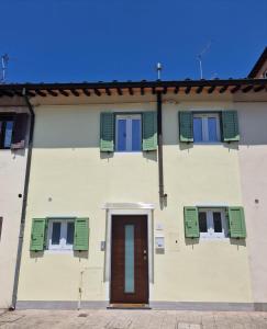 um edifício branco com persianas verdes e uma porta em Casina Elena - Viareggio centro em Viareggio