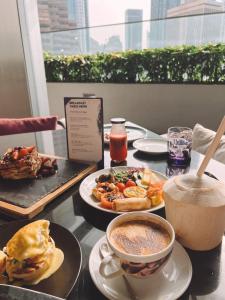 a table with plates of food and a cup of coffee at W Kuala Lumpur Hotel in Kuala Lumpur