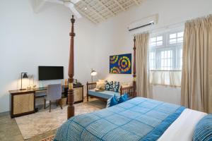 a bedroom with a bed and a desk and a television at Ceylo Villas in Bentota