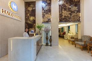 a woman standing at a counter in a hotel lobby at HALO HANOI HOTEL in Hanoi