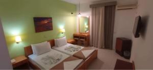 Olympic Hotel في كارباثوس: غرفه فندقيه سرير وتلفزيون