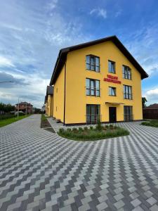 a yellow building on the side of a road at Yellow apartments in Boryspilʼ