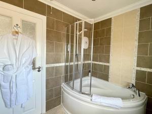 y baño con bañera, ducha y toalla. en Bojangles Guest House, en Gretna Green