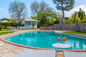 ein Pool mit zwei Gläsern auf Tischen davor in der Unterkunft Resort Ravenna in Massa Lubrense