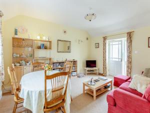 a living room with a table and a red couch at Robin Cottage in Temple Combe