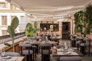 ein Restaurant mit Tischen, Stühlen und Pflanzen in der Unterkunft Hotel El Pilar Andalucia in Estepona