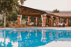 a resort with a pool and people sitting at tables at Hotel Storia in Čapljina