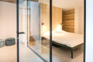 a bedroom with a bed and a glass wall at WOWieGermain Luxueus vakantiehuis voor families, vlak bij het strand in Oostduinkerke